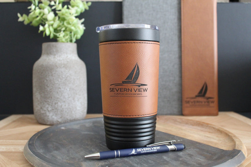 Personalized leather-wrapped tumbler and engraved business pen featuring a custom company logo, displayed with matching leather notebook.